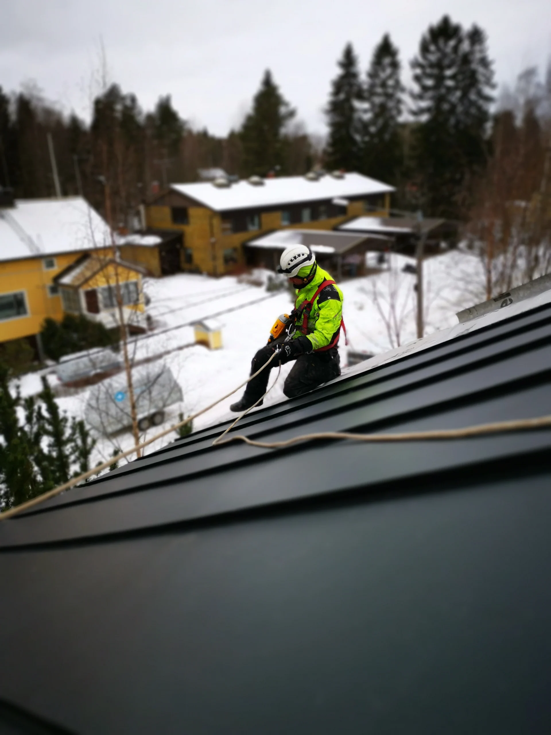 Kattoasentaja tekemässä huoltoa ja katon kuntotarkistusta turvaköydellä.